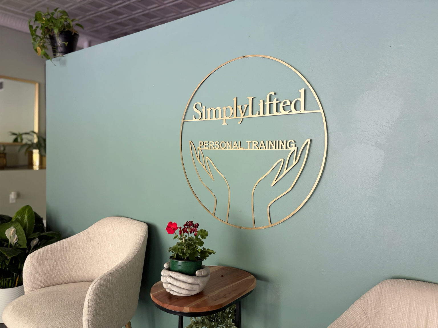 SimplyLifted private studio interior with the gold hands logo on a sage wall